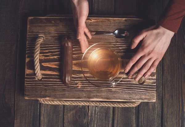 Çay ve pasta ahşap masa üzerinde elleriyle — Stok fotoğraf