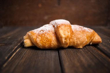 kruvasan ahşap masa üzerine pudra şekeri ile