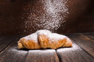 kruvasan düşen pudra şekeri ile ahşap masa