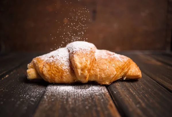 kruvasan ahşap masa üzerine pudra şekeri ile