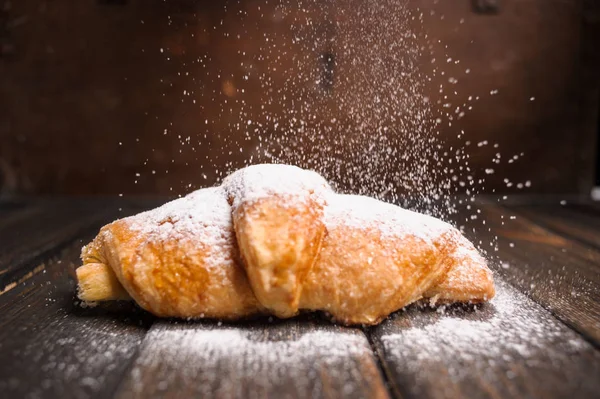 kruvasan düşen pudra şekeri ile ahşap masa