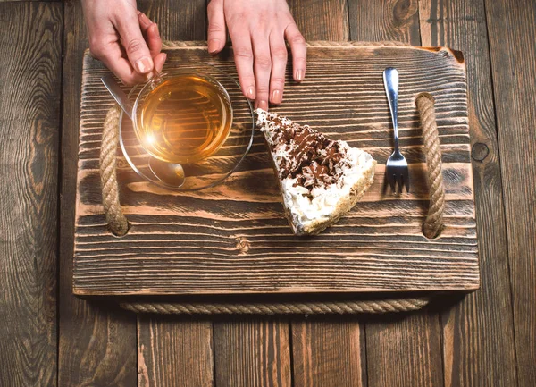 Çay ve pasta ahşap masa üzerinde elleriyle — Stok fotoğraf