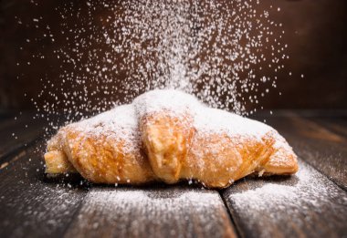 kruvasan düşen pudra şekeri ile ahşap masa