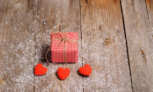 Herz auf hölzernem Hintergrund mit Schnee und Geschenkbox — Stockfoto