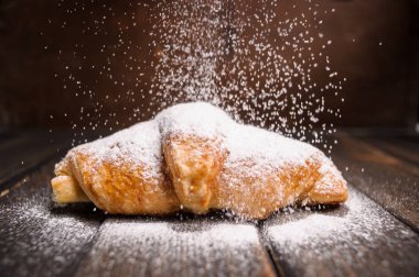 kruvasan düşen pudra şekeri ile ahşap masa