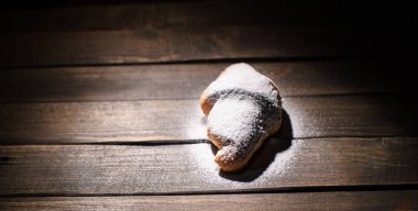 kruvasan ahşap masa üzerine pudra şekeri ile