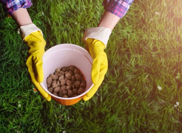 Gleby w ręce kobiety, plastikowe doniczki na tle trawy — Zdjęcie stockowe