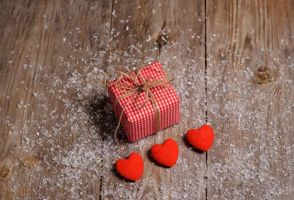 Heart on a wooden background with snow and gift box — Stock Photo, Image