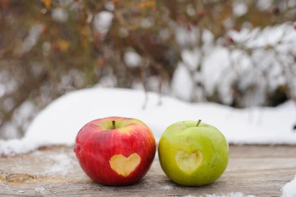 green and red apples with hearts in it on the snow