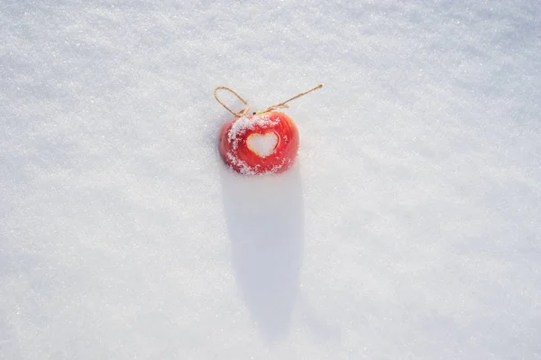 red apple with heart on the snow