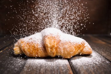 kruvasan ahşap masa üzerine pudra şekeri ile