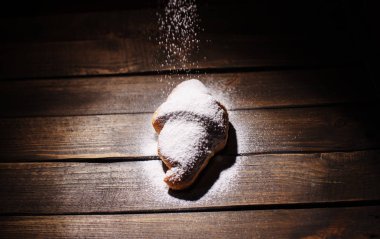 kruvasan ahşap masa üzerine pudra şekeri ile