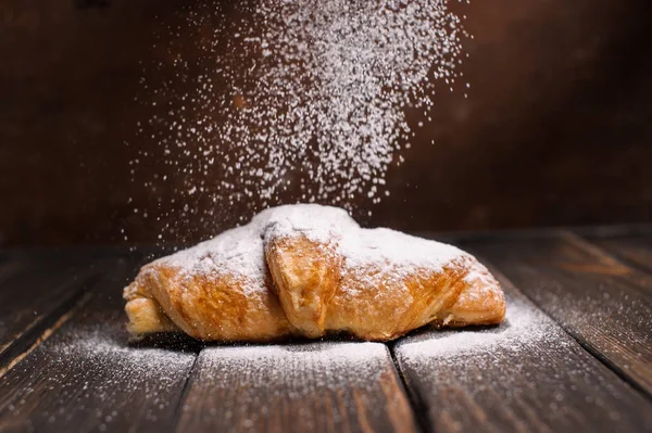 kruvasan düşen pudra şekeri ile ahşap masa