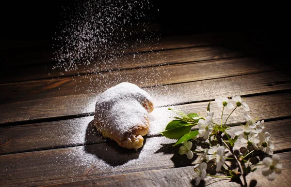 Croissant en escritorio de madera con azúcar en polvo que cae — Foto de Stock