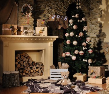 Arka planda ağaç hediyeleri ve şömineli Noel sahnesi