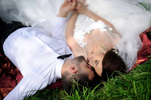 Szczęśliwy wesele para leżącego na zielonej trawie w okresie letnim — Zdjęcie stockowe