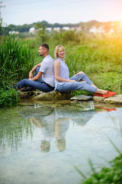 Coppia d'amore seduta sulla roccia al fiume e vista sul tramonto — Foto Stock