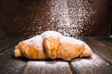 kruvasan ahşap masa üzerine pudra şekeri ile