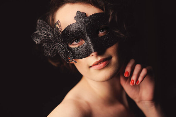 Beauty model woman wearing venetian masquerade carnival mask at party isolated on black background. Christmas and New Year celebration.