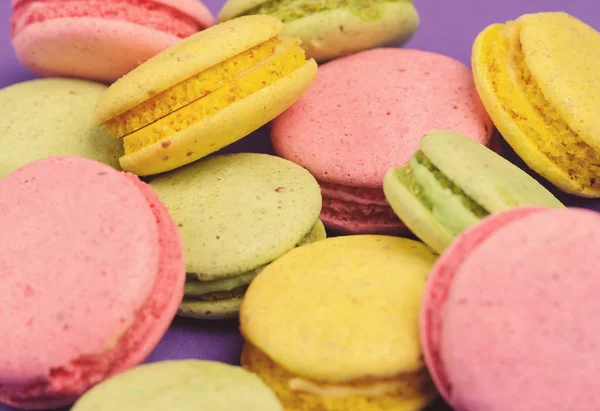 Tatlı ve renkli Fransızca macaroons veya mor zemin üzerine macaron