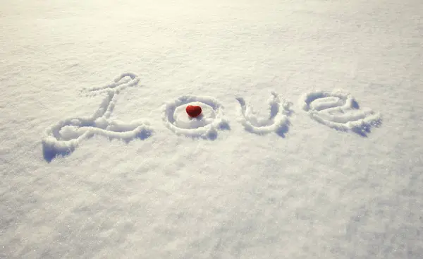 Palabra amor y corazón rojo en la nieve — Foto de Stock