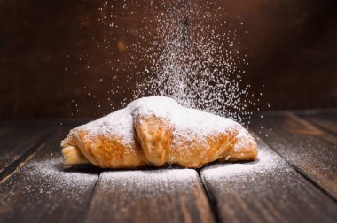 kruvasan düşen pudra şekeri ile ahşap masa