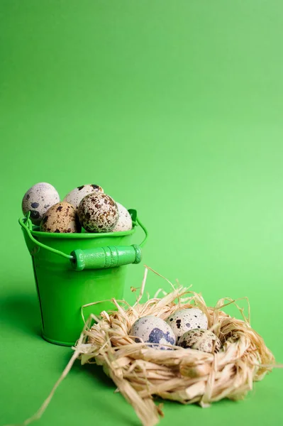 Kleine dekorative Eimer gefüllt Wachteleier auf dem grünen Hintergrund — Stockfoto