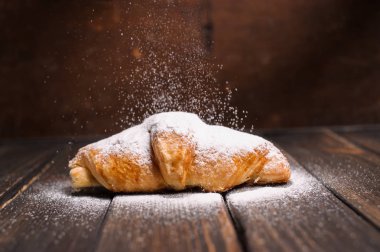 kruvasan düşen pudra şekeri ile ahşap masa