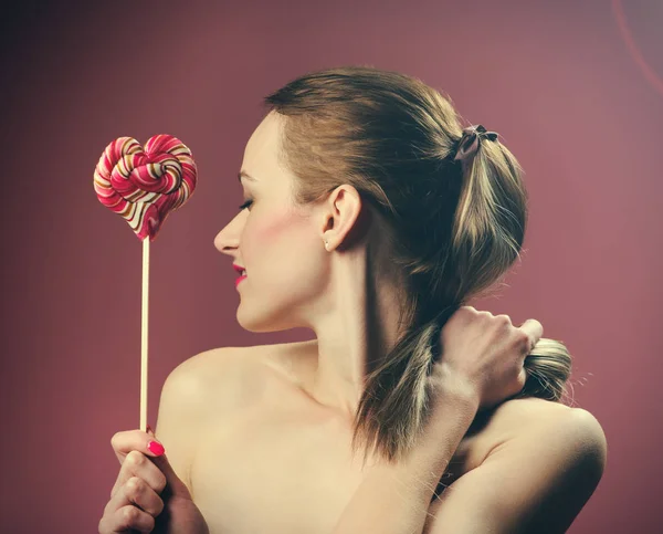 Emotional girl with a lollipop over pink background — Stock Photo, Image