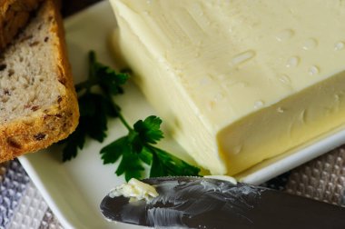 ahşap bir masada bıçak, ekmek ve maydanoz ile tereyağı parçası