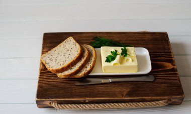 ahşap bir masada bıçak, ekmek ve maydanoz ile tereyağı parçası