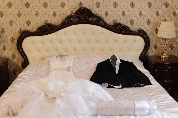 美しくエレガントな白いウェディングドレスと結婚式のお祝いを期待してベッドの上の男性新郎新婦のウェディングスイート — ストック写真