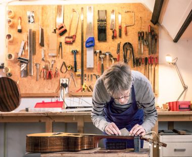 Craftsman in his workshop leveling the frets of a guitar clipart