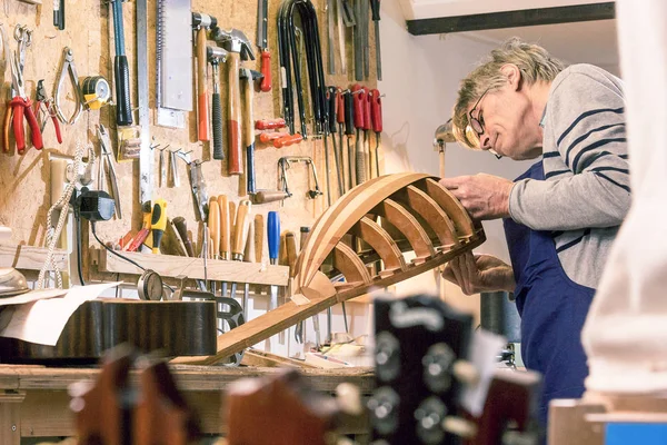 Luthier inspecionando seu alaúde meio acabado — Fotografia de Stock