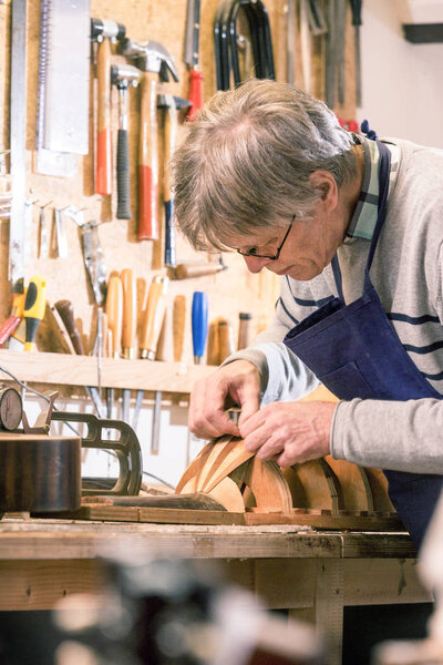 Luthier carefully carving the shape of a lute
