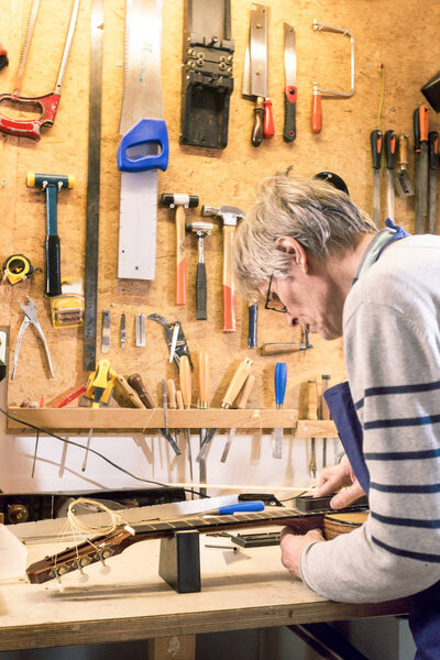 Luthier filing the frets of an acoustic guitar