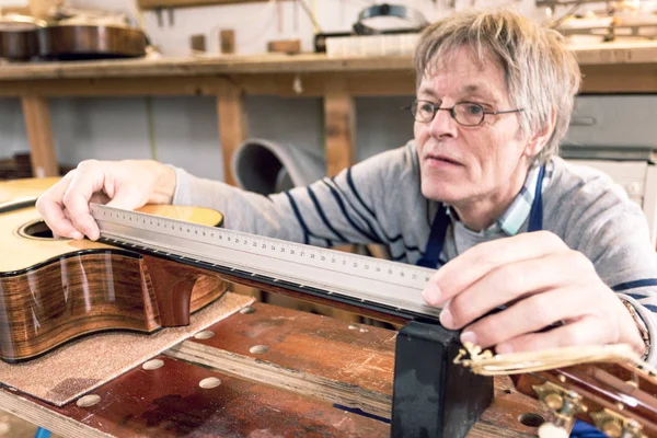 Человек измеряет лады на гитаре — стоковое фото