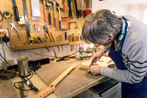 Luthier filing the neckpocket of an electric guitar