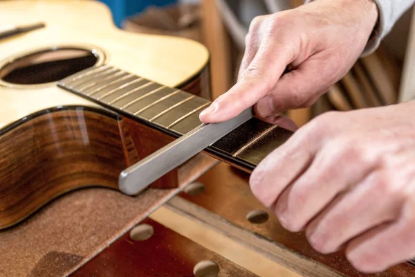 Mãos de artesão, arquivando os trastes de uma guitarra — Fotografia de Stock