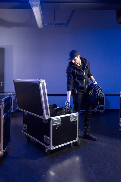 Roadie picking some cables out of a flightcase — Stock Photo, Image