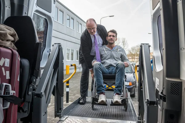 Driver helping man on wheelchair — Stock Photo, Image