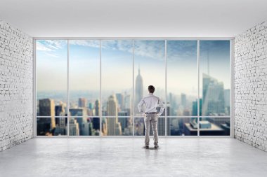 Büyük pencereler ile parlak bir temiz oda ayakta iş adamı