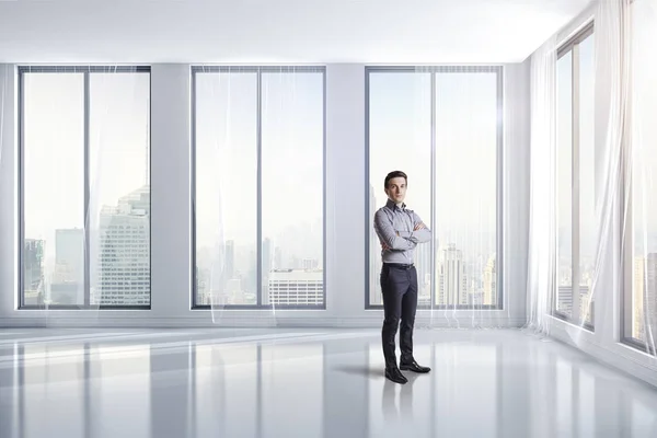 Бизнесмен стоит в светлой чистой комнате с большими окнами — стоковое фото