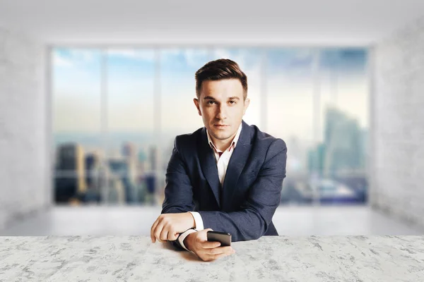 Attractive businessman with modern suit sitting against modern office view — Stock Photo, Image