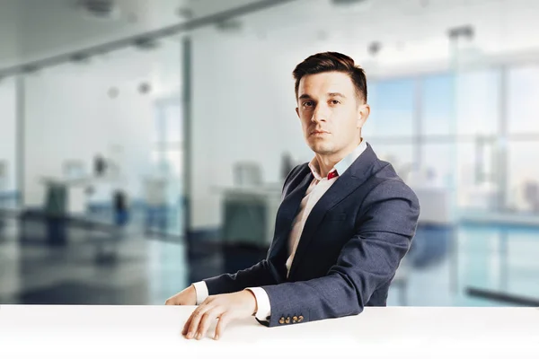 Attractive businessman with modern suit sitting against modern office view — Stock Photo, Image