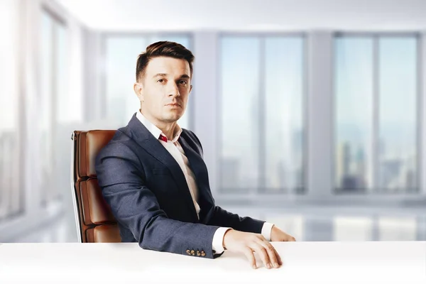 Привабливий бізнесмен з сучасним костюмом, що сидить на тлі сучасного вигляду офісу — стокове фото