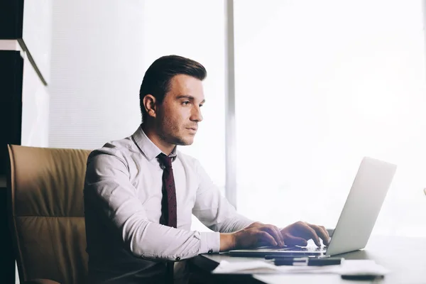 Attraktiver Geschäftsmann in schicker Freizeitkleidung sitzt an seinem Arbeitsplatz im Büro — Stockfoto