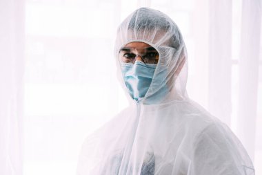 Erkek doktor ya da bilim adamı koruyucu giysi ve yüz maskesi giyiyor. 