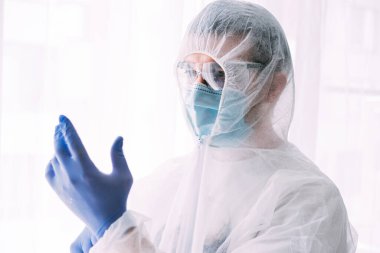 Erkek doktor ya da bilim adamı koruyucu giysi ve yüz maskesi giyiyor. 