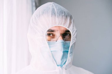 Erkek doktor ya da bilim adamı koruyucu giysi ve yüz maskesi giyiyor. 